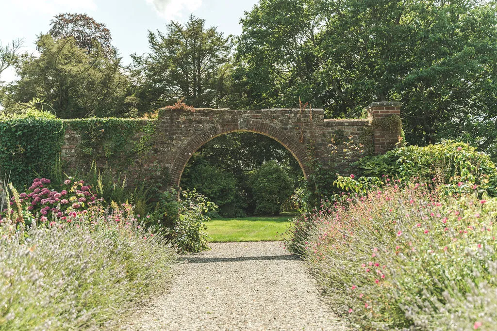 A stone arch in the walled garden surrounded by wildflowers